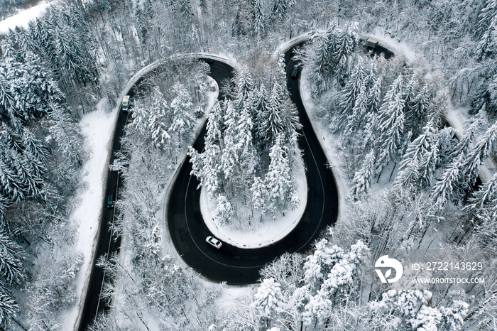 Bent road in the forest with cars passing by