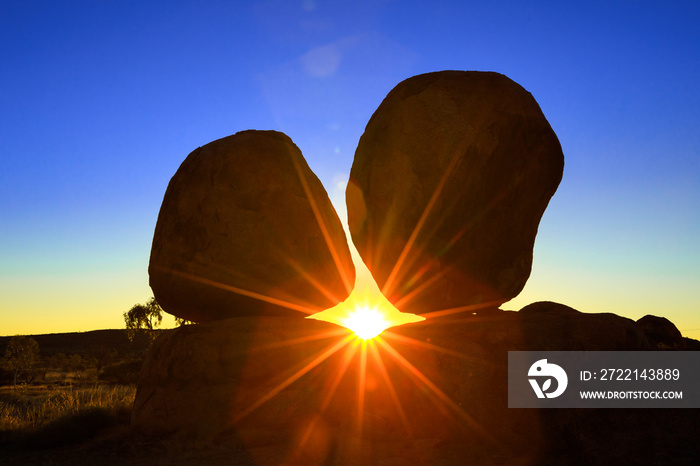 Sunbeams at dawn behind iconic Devils Marbles: Eggs of mythical Rainbow Serpent. Karlu Karlu Devils Marbles Conservation Reserve is one of Australia’s most famous natural wonders in Northern Territory