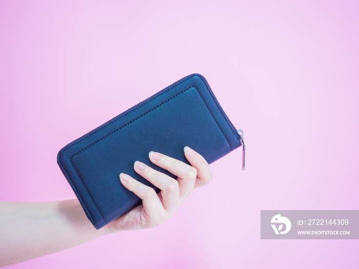 asian woman hold her blue purse by left hand with pink pastel background