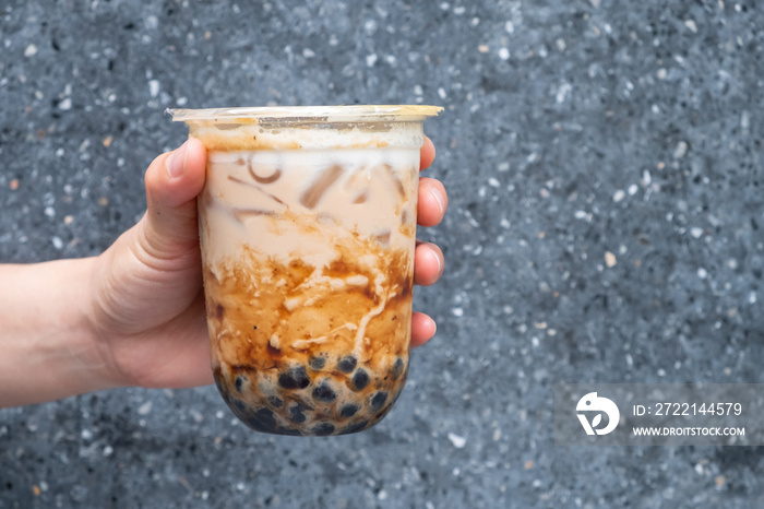 Cropped shot of someone hand holding a cup of iced Bubble milk tea. Bubble tea was a traditional drink in Taiwan before it became hugely popular all over the world.