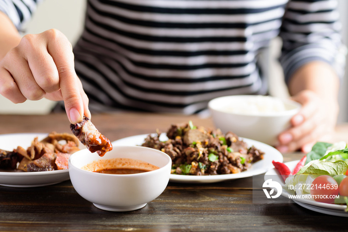 Local Northern Thai food, spicy minced pork salad (Larb Moo Kua) eating with grilled pork dip in chili sauce by hand