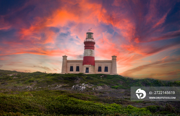 Cape Agulhas lighthouse in the southernmost part of South Africa where the Atlantic Ocean divides from the Indian Ocean, with a very beautiful and spectacular sunset sky.