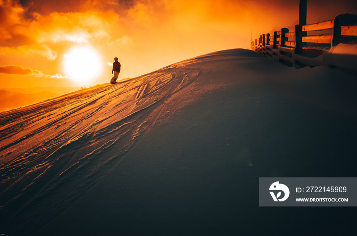 Silhouette of snowboarder in ski resort, Colorful sunset in background, edit space