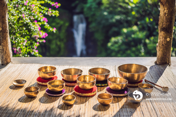 Tibetan singing bowls on a straw mat against a waterfall