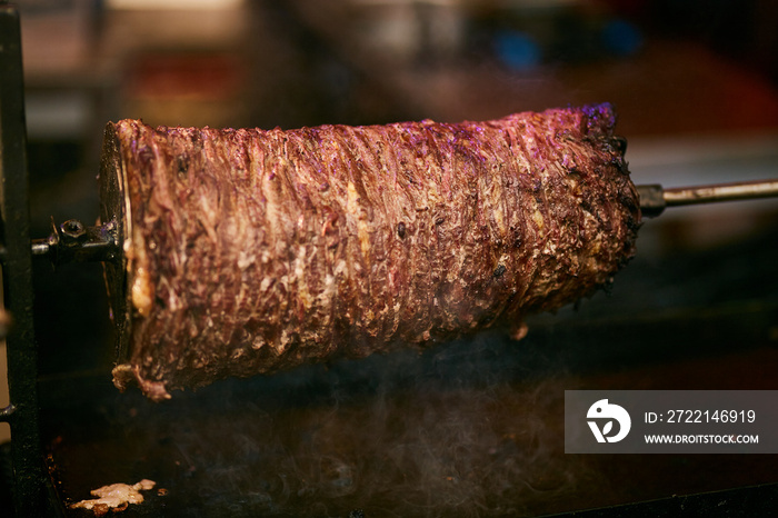 Doner Kebab On Rotating Spit. Traditional Turkish food Doner Kebab. Turnspit skewing kebap or kebab on metal skewer in the kebab restaurant. Shawarma meat cooking and turning. shawarma. close up