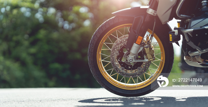 Part of a motorcycle wheel, tire, parked on a beautiful road. motorcycle in a sunny motorbike on the road riding.with sunset light. copyspace for your individual text.