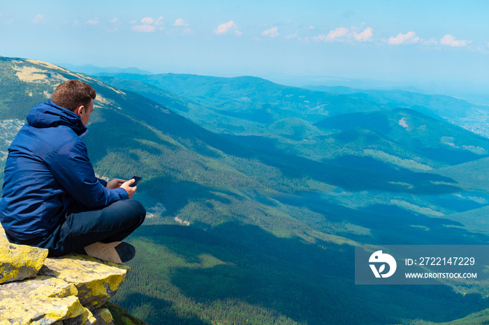 young guy makes a photo on the phone in the mountains