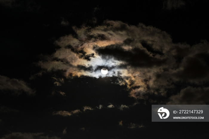 Full moon with clouds and colorful corona, also called aureole (optical phenomenon).