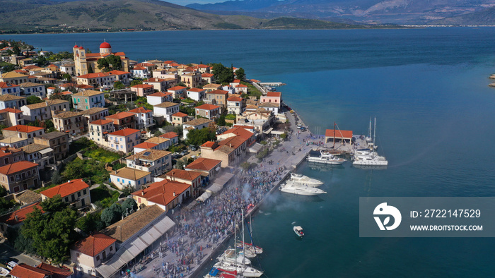 Aerial drone bird’s eye view photo of people participating in traditional colourful flour war or Alevromoutzouromata part of Carnival festivities in historic port of Galaxidi, Fokida, Greece