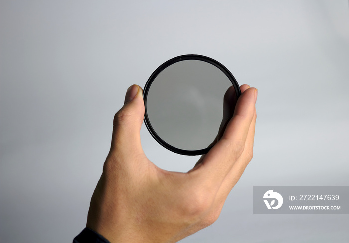 Hand holds ND lens camera filter on white background