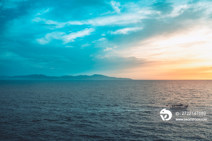 Amazing colorful sky sunrise above mountains and deep blue ocean with fishing boat