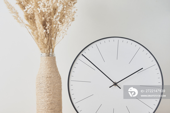 Classic round clock and homemade vase with a dries plant closeup