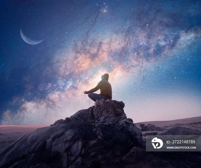 person meditating outdoors at night under the Milky Way and Moon