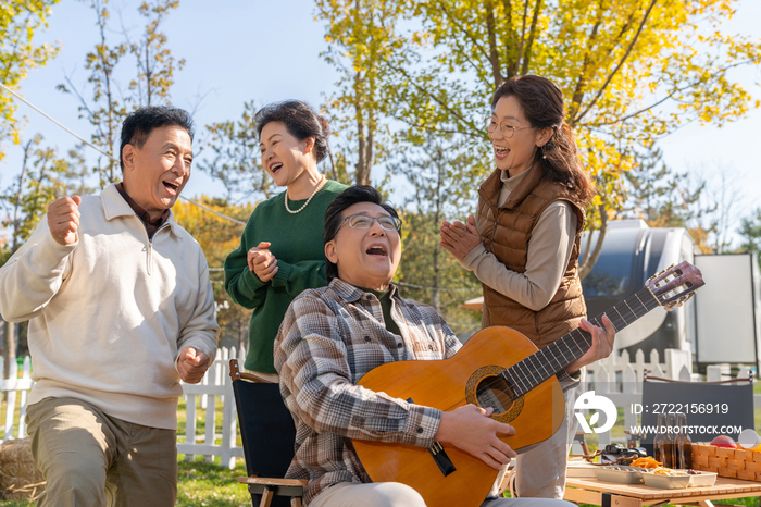 一群中老年人在房车露营地弹吉他唱歌