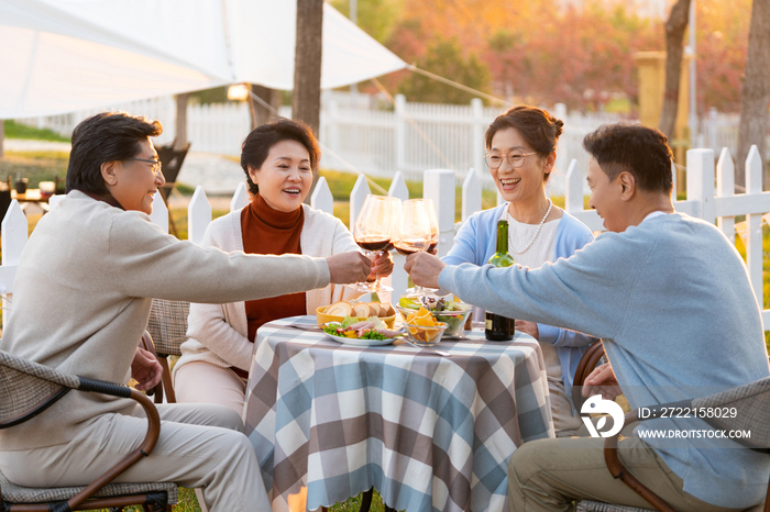 夕阳下中老年朋友在庭院里聚会喝酒聊天