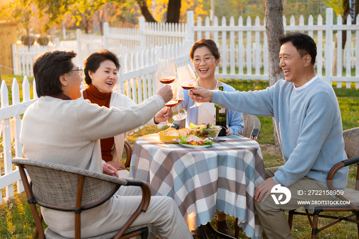 夕阳下中老年朋友在庭院里聚会喝酒聊天