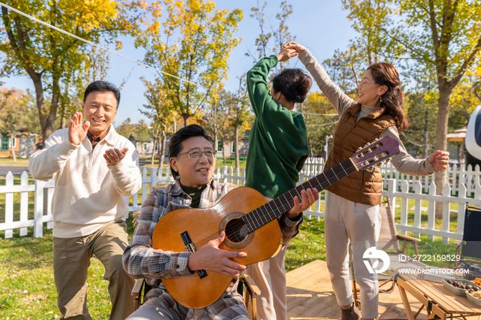 一群中老年人在房车露营地弹吉他唱歌