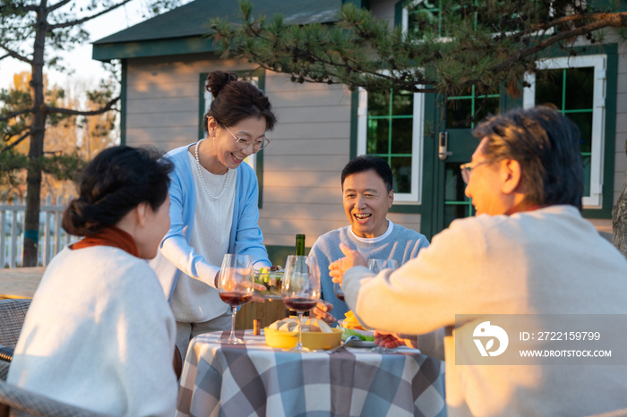 夕阳下中老年朋友在庭院里聚会喝酒聊天