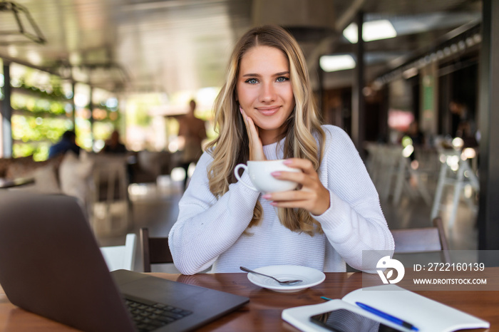 Young woman using portable laptop computer while sitting in a coffee shop