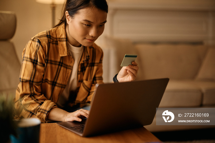 Asian woman shopping on internet with credit card and laptop at home.