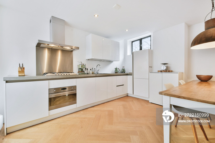 Interior of spacious kitchen with white cabinets and stainless extractor hood and black counter