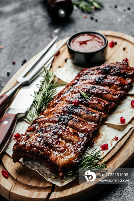 Pork ribs grilled with BBQ sauce. Tasty snack on wooden board. Food recipe background. Close up