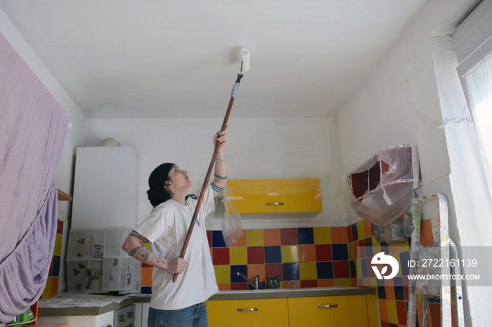 Femme peignant un plafond au rouleau