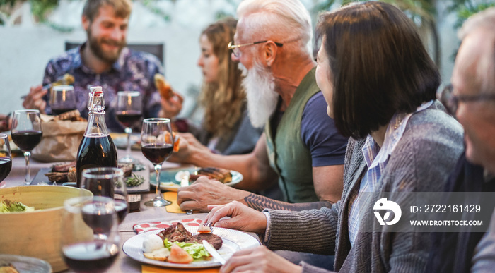 Happy family eating and drinking wine at barbecue dinner outdoor - Mature and young people having fu