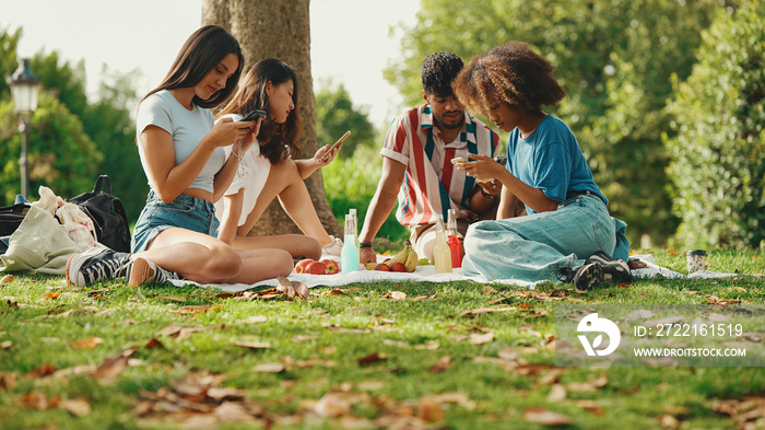 Close-up of young man with curly hair wearing striped shirt sitting in park having picnic on summer 