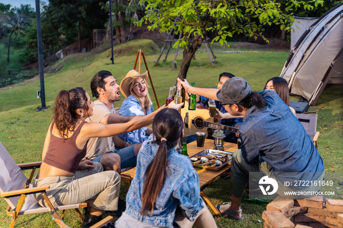 Group of diverse friend having outdoors camping party together in tent.