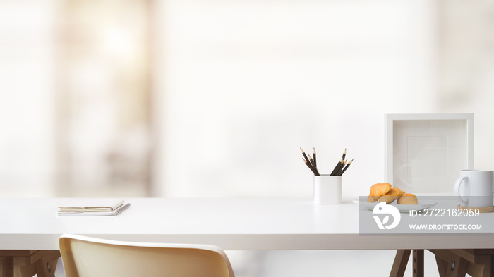 Close up view of workspace with copy space, frame, stationery, coffee cup and croissant on white tab