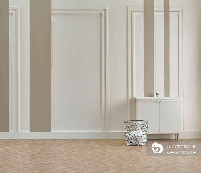 Bath room, white and brown wall, cabinet sink and laundry clothes, vase of plant, lamp.