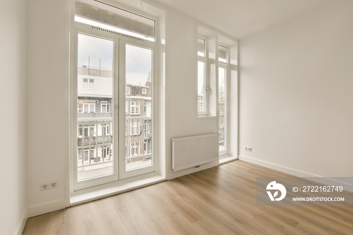 an empty room with wood floors and white walls, there is a large window that looks out onto the stre