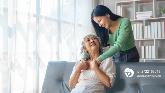 60s asian mother elderly sitting on sofa with young asia female daughter together in living room. ha