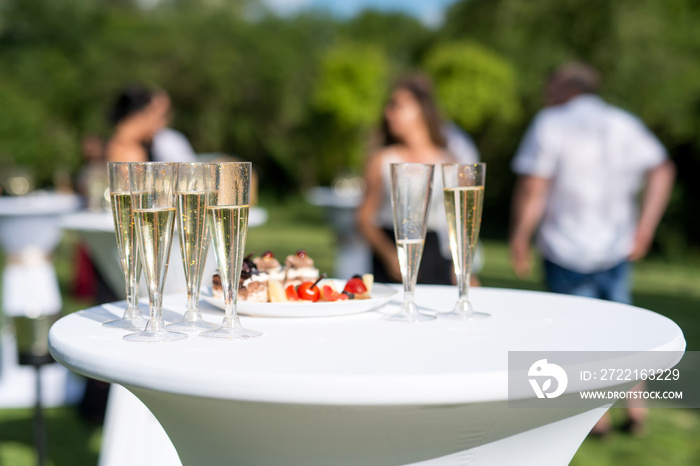 Welcome drink, view of glasses filled with champagne on a table in a garden - selective focus