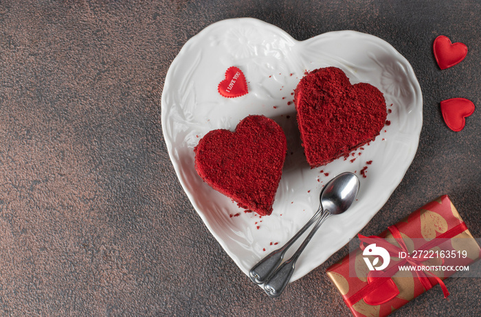 Cakes Red velvet in the shape of hearts on white plate, roses and wine for Valentines Day on brown b