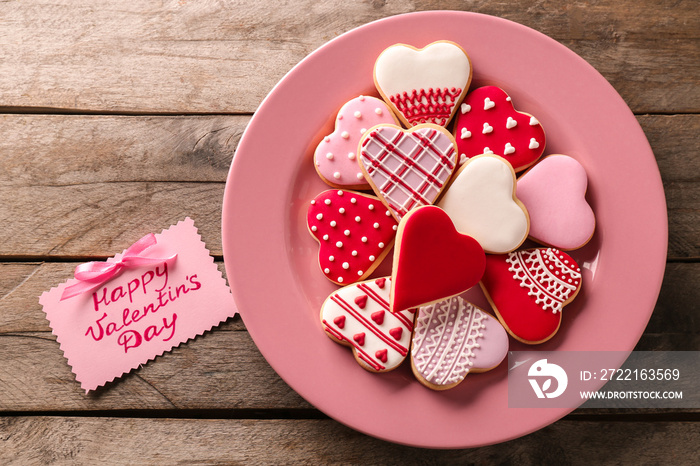 Heart shaped glazed cookies and Valentine card on wooden background