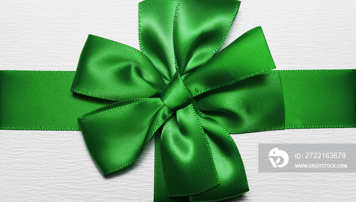 Close-up of green wrapping ribbon in shape of bow for white gift box.