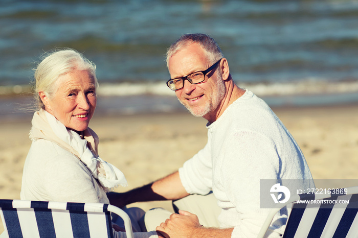 senior couple sitting on chairs at summer beach