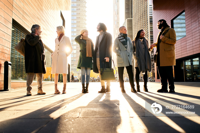 Silhouette of a group of business people full body talking outdoors in the city street. Man and woma