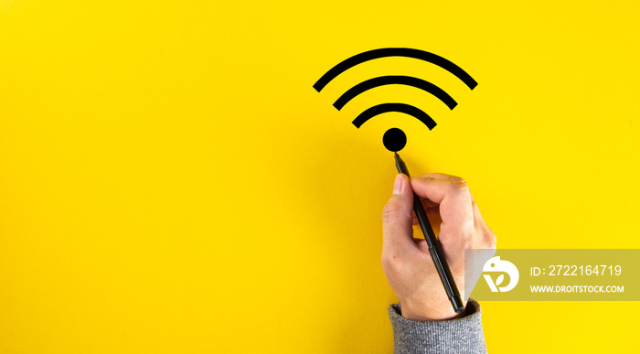 A male hand drawing a wifi signal on yellow color background with copy space.