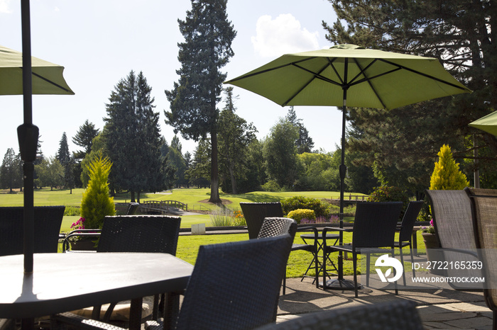 Sunlit patio with table, chairs and umbrella with view of golf course greens