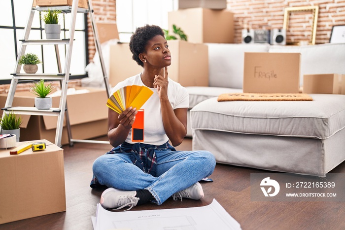 African american woman choosing paint color sitting on floor at new home