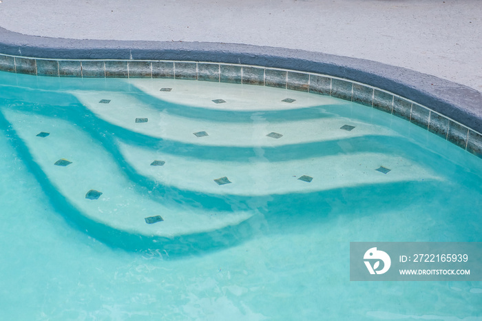 Pool steps in a large free form gray grey accent swimming pool with turquoise blue water