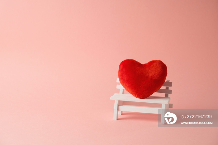 Valentines day minimal concept with red heart shape on bench over pink background