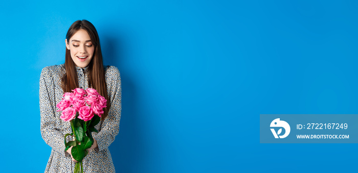 Valentines day concept. Happy attractive woman receive surprise flowers, looking thankful at bouquet