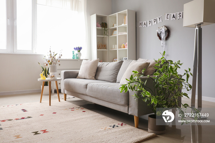 Interior of living room with sofa, tree branches and Easter eggs