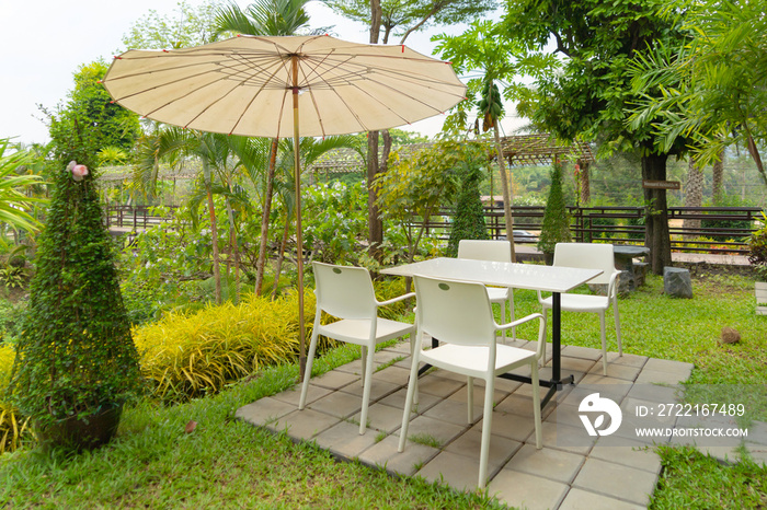 Relax table, chairs and umbrellas in park garden. Outdoor restaurant