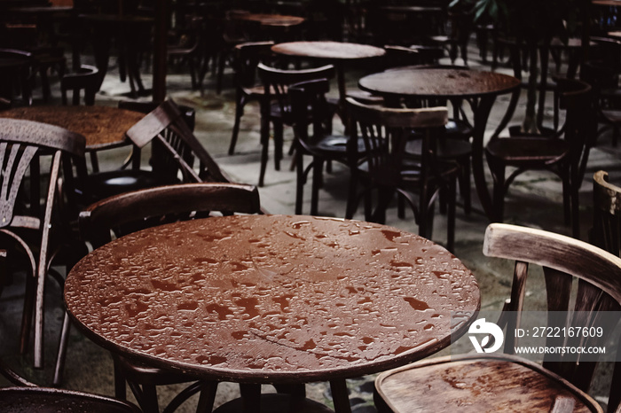 stylish wooden chairs and tables empty at rainy day on streets of europe city