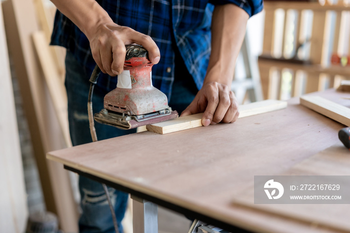 Craftsman hands polishing wooden table with machine.